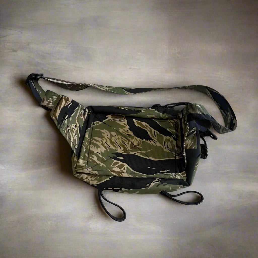 Camouflage-patterned waist bag on a textured surface with a tag.
